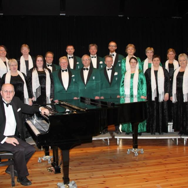 Rökkurkórinn ásamt stjórnandanum, Thomasi R. Higgerson. Mynd af fésbókarsíðu kórsins.