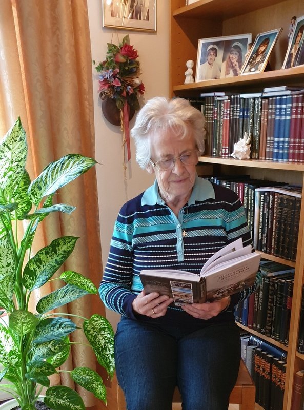 Helga Bjarnadóttir blaðar í Blómarósum í Blönduhlíð. Sögu kvenfélags Akrahrepps . Aðsend mynd.