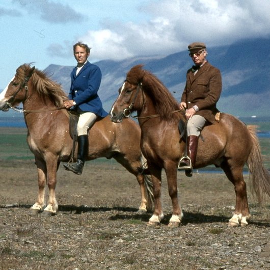 Fyrri mynd: Mynd frá landsmótinu á Vindheimamelum 1974. Til vinstri er Núpur frá Kirkjubæ, sigurvegari í flokki alhliða gæðinga á mótinu, setinn af eiganda sínum Sigurfinni Þorsteinssyni klæddum í félagsbúning FT að vísu ekki með rautt bindi, þess í stað með klút. Til hægri Jóhann Friðriksson í Kápunni afar smekklega klæddur í brúntóna sjatteringu, buxurnar drappleitar og reiðstígvélin brún leðurstígvél. Hesturinn sem Jóhann situr er óþekktur en gæti verið afkvæmi Blesa frá Núpakoti (577) eins og Núpur sjálfur en Blesi var sýndur með afkvæmum á mótinu og hlaut Sleipnisbikarinn. Ljósmynd úr safni SÍH, ljm.: Friðþj. Þorkelsson.