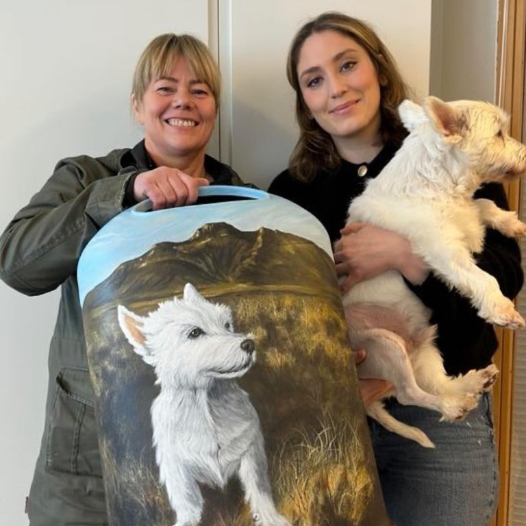 Hér sjáið þið fallegu tunnuna sem Gígja Heiðrún skapaði. Það er Gígja Heiðrún sem heldur á  tunnunni og Alexandra Jóhannesdóttir, sveitarstjóri, sem heldur á Olla sæta. Mynd tekin af Facebook-síðu Skagastrandar.