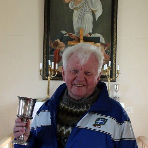 Greinarhöfundur í Tjarnarkirkju á Vatnsnesi með bikar sem Guðmundur Ketilsson fékk 1853 fyrir umbætur á leigujörð sinni frá Konunglega danska landbúnaðarfélaginu. Bikarinn gaf hann í Tjarnarkirkju og var hann um árabil notaður þar sem kaleikur. Aðsend mynd.