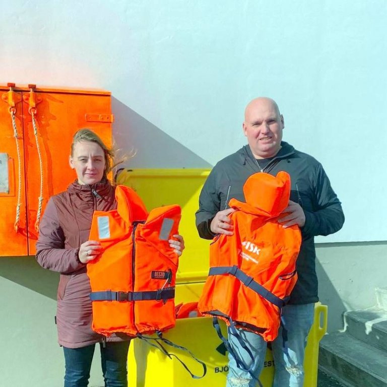 Stefanía Sigurðardóttir, gæða- og öryggisstjóri FISK Seafood, afhendir Degi Baldvinssyni, hafnarstjóra, björgunarvesti sem bryggjugestir geta fengið lánuð og aukið þar með öryggi sitt. Mynd aðsend.