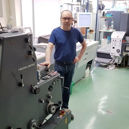 Guðni Friðriksson við gömlu GTO 52 eins lita prentvélina sem gerði það mögulegt að prenta Feyki í heimabyggð. Að baki Guðna er fjórlitaprentvélin sem nú sinnir því hlutverki að prenta Feyki, og allt í lit. Mynd: PF.