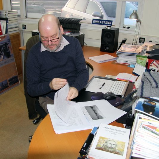 Óli Arnar Brynjarsson blaðar í handriti 10. Byggðasögu Skagafjaraðar sem nú er verið að setja upp í Nýprenti á Sauðárkróki. Mynd: PF.