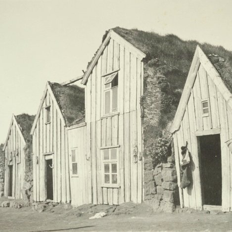 Torfbær með fjórum burstum. Fyrir framan bæinn stendur kona sem styður hendi undir kinn. Myndin er tekin á árunum 1925-1935. Ljósm. Þjóðminjasafn Íslands.